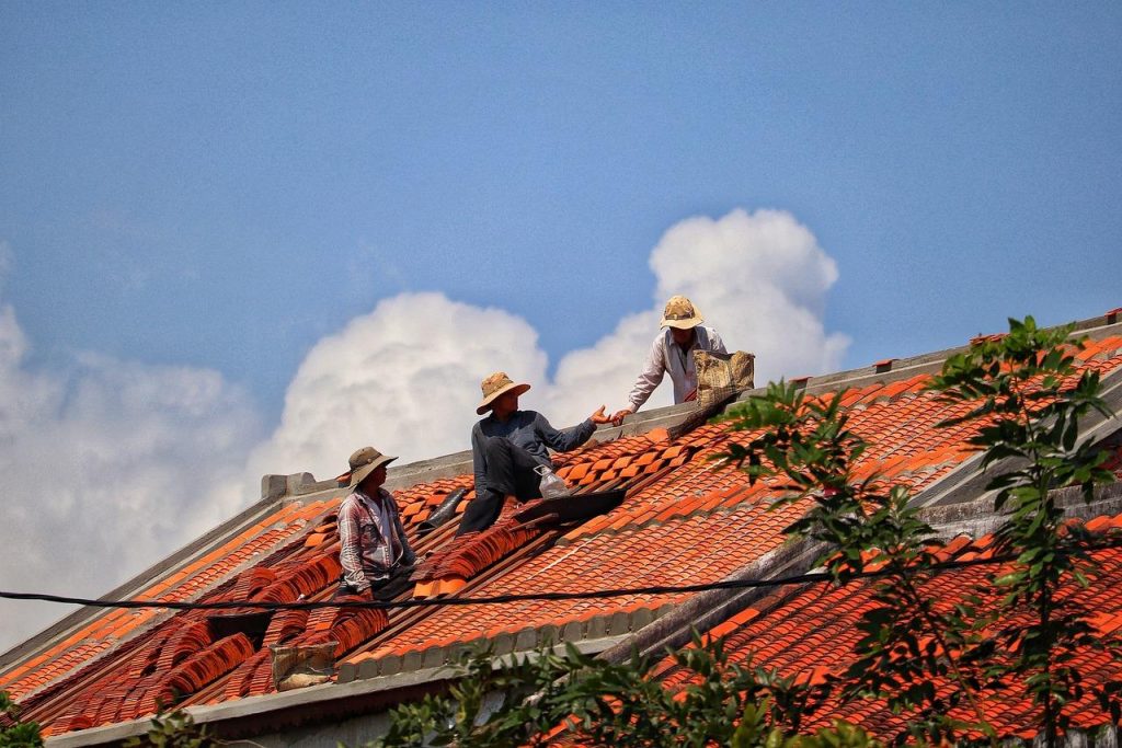 Professional voert spoed dakreparatie uit aan dakpannen tijdens regenweer om lekkages te voorkomen